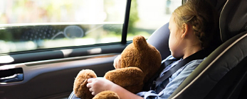 child alseep in car seat holding teddy bear