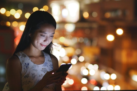 A woman a night using her mobile phone.